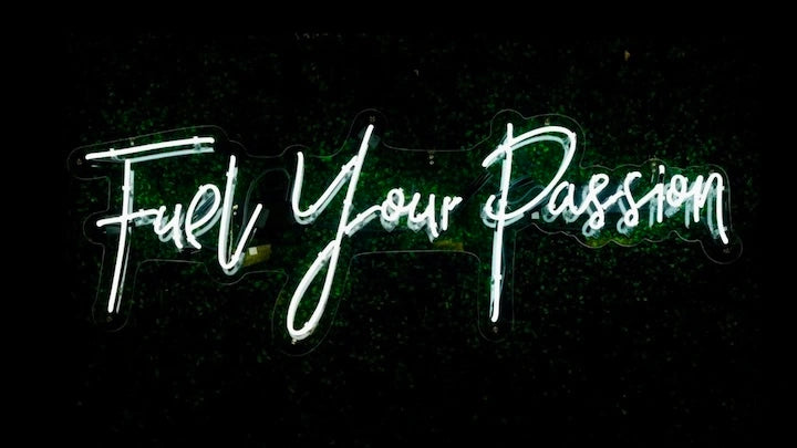 Eine leuchtende Neonschrift mit dem Text: Fuel your Passion. Die Neonschrift ist vor einem schwarzen Hintergrund.